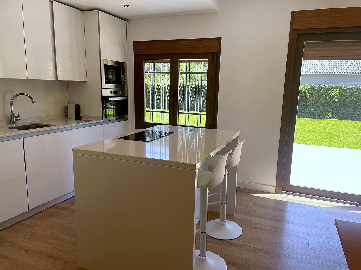 Cocina con isla y taburetes, con vistas al jardín
